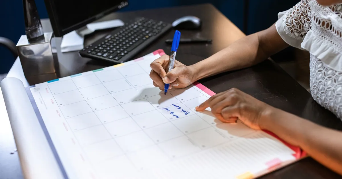 Writing an appointment note in a desk calendar with a pen
