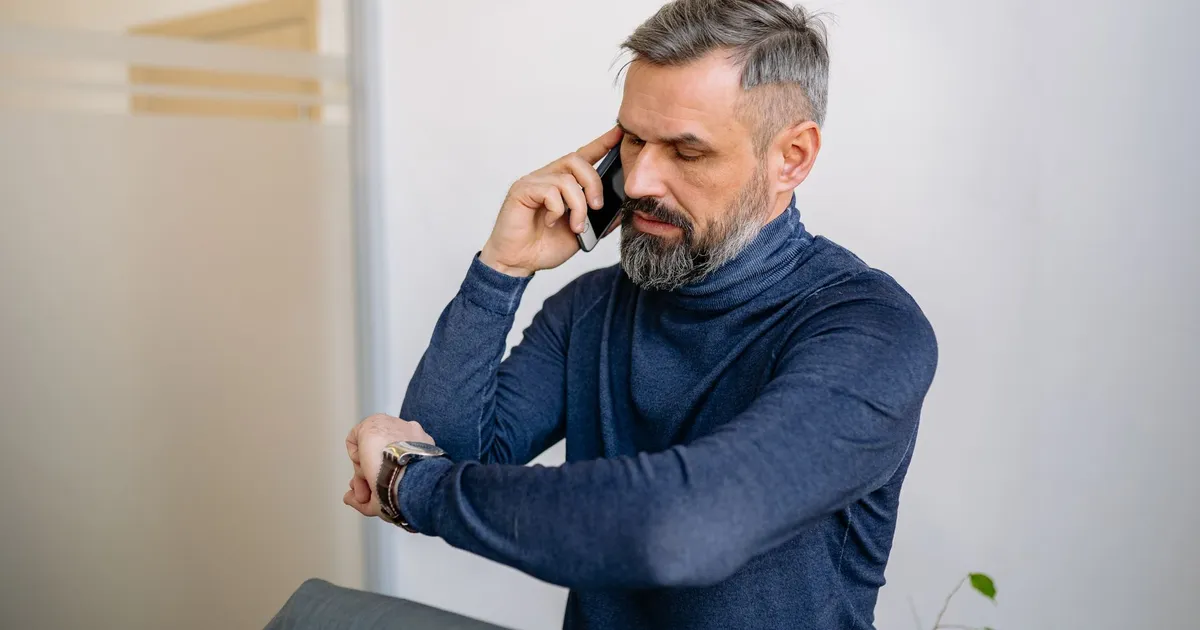 Professional checking the time on his phone before sending an appointment reminder SMS