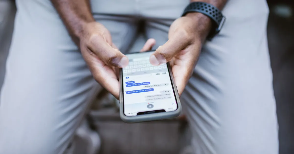 Close-up of hands typing an appointment reminder message on a phone