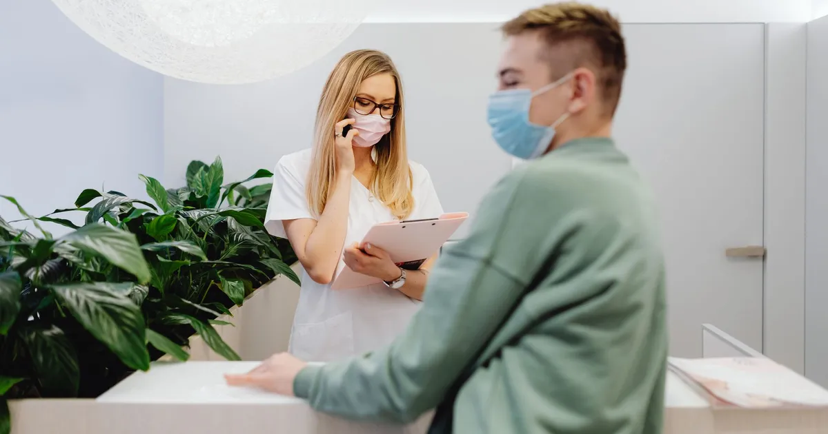 Medical practice reception desk with a staff member assisting a patient